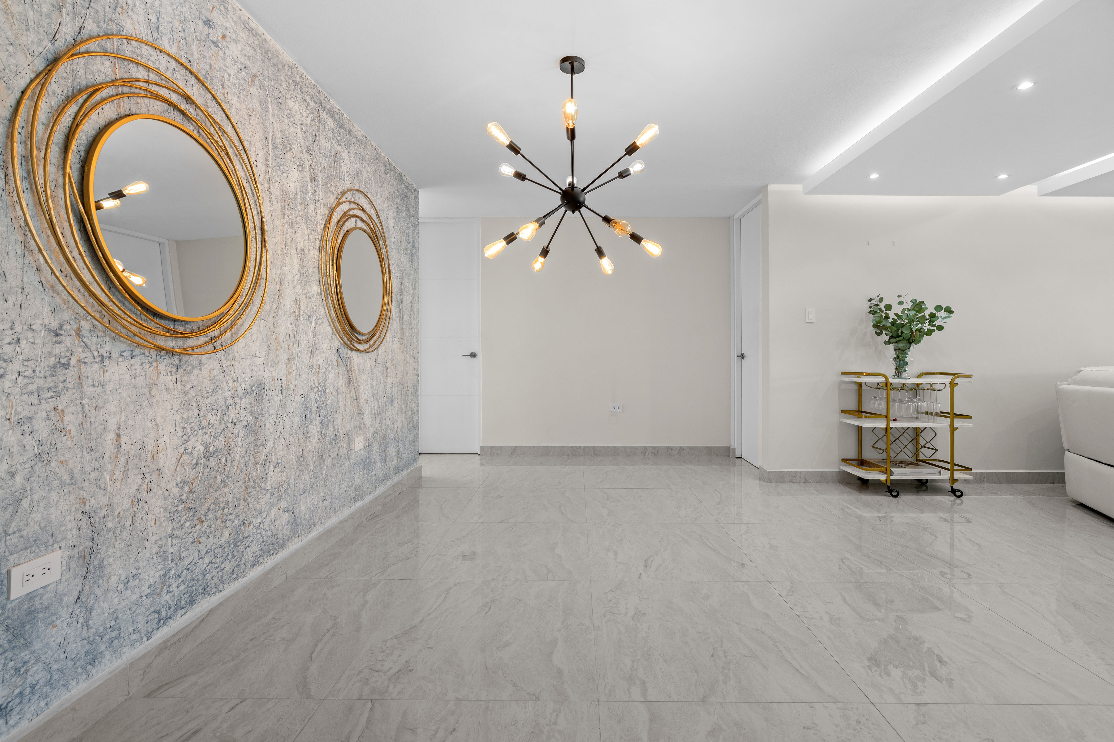 Astralis Isla Verde living area with accent wall modern chandelier and open layout design