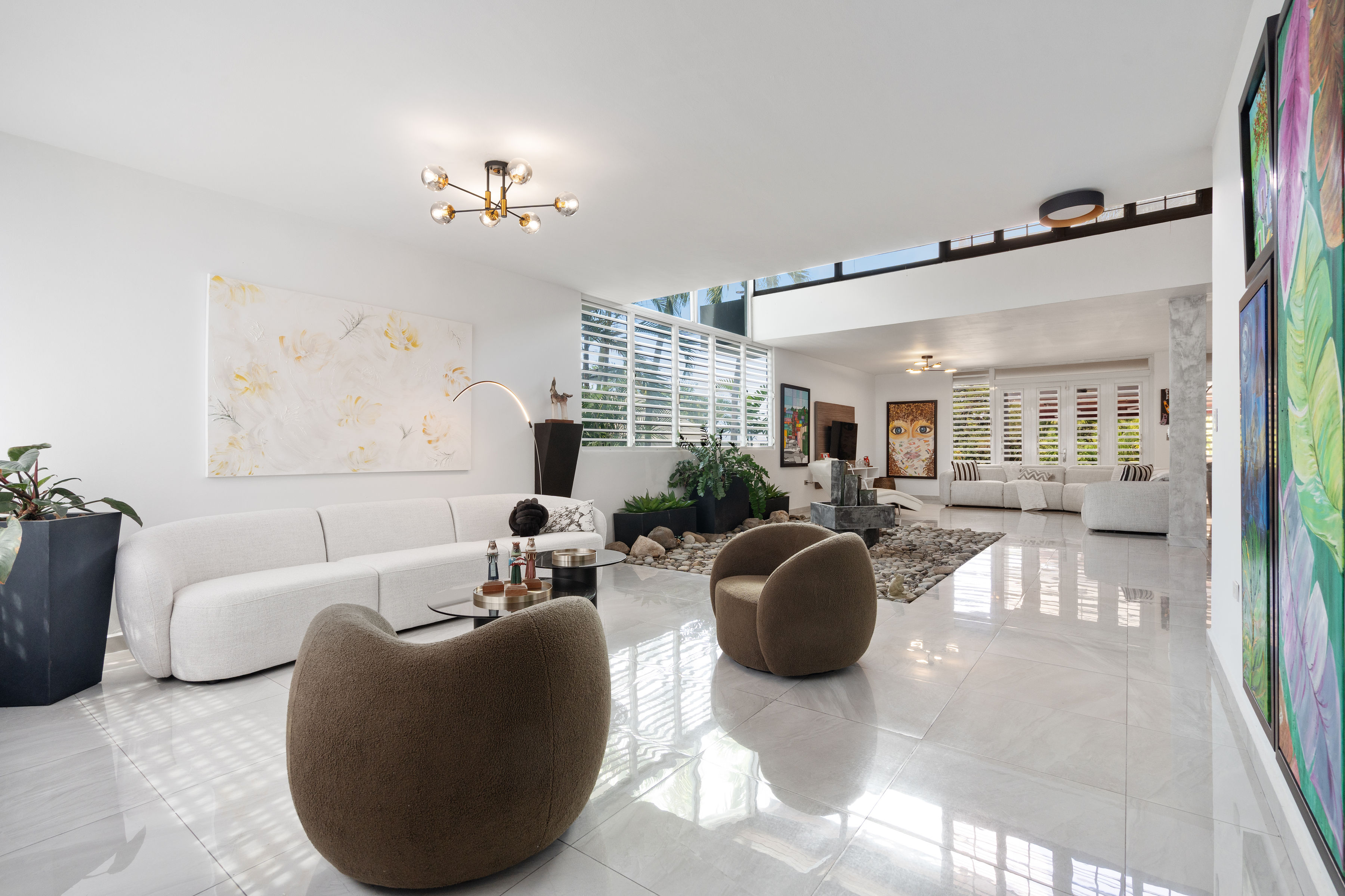 Modern open concept living room with high ceilings and indoor garden fountain in Mansiones de Villanova San Juan