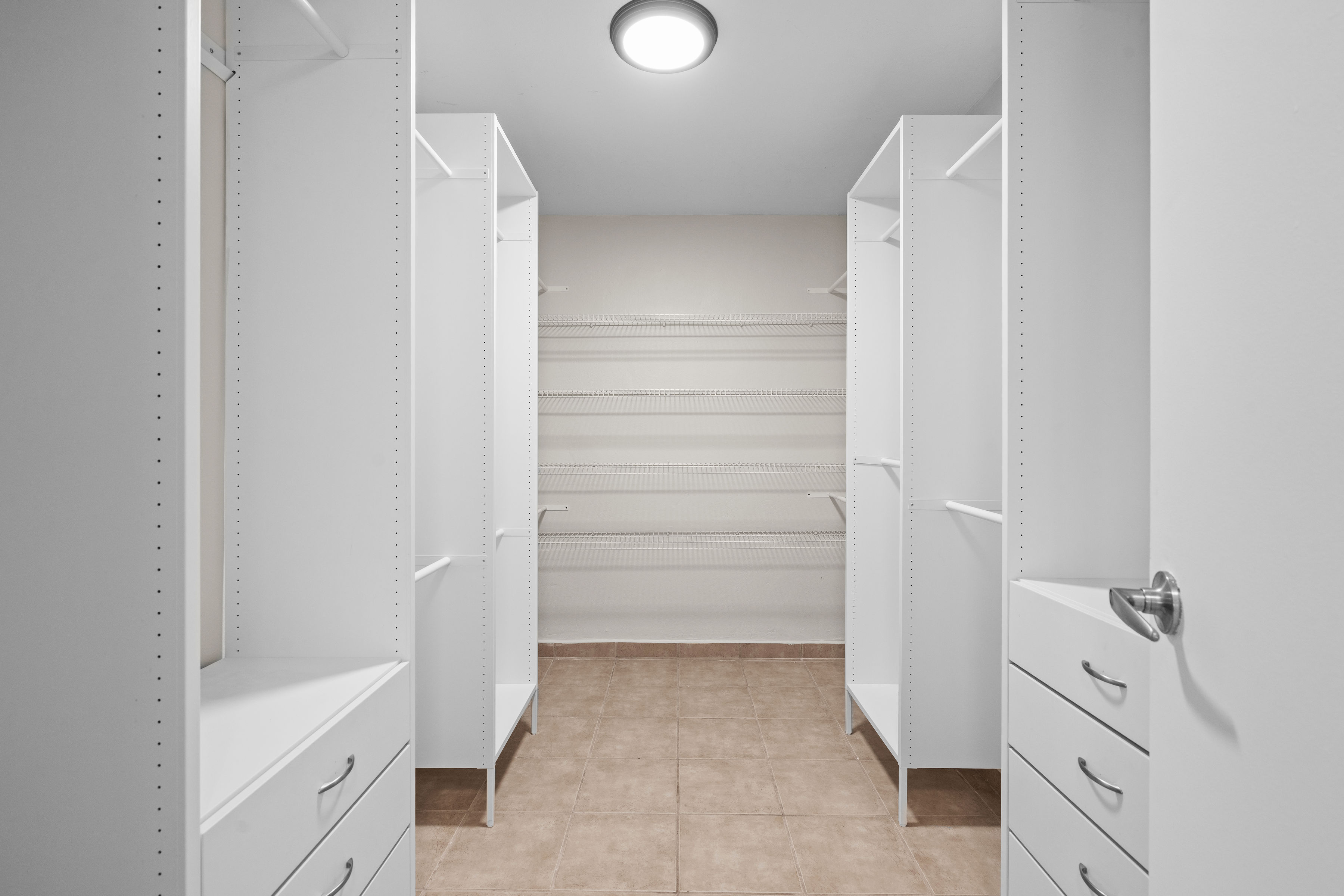 Walk-in closet with built-in shelving and organized storage space in primary bedroom in Cielo Dorado Village residence