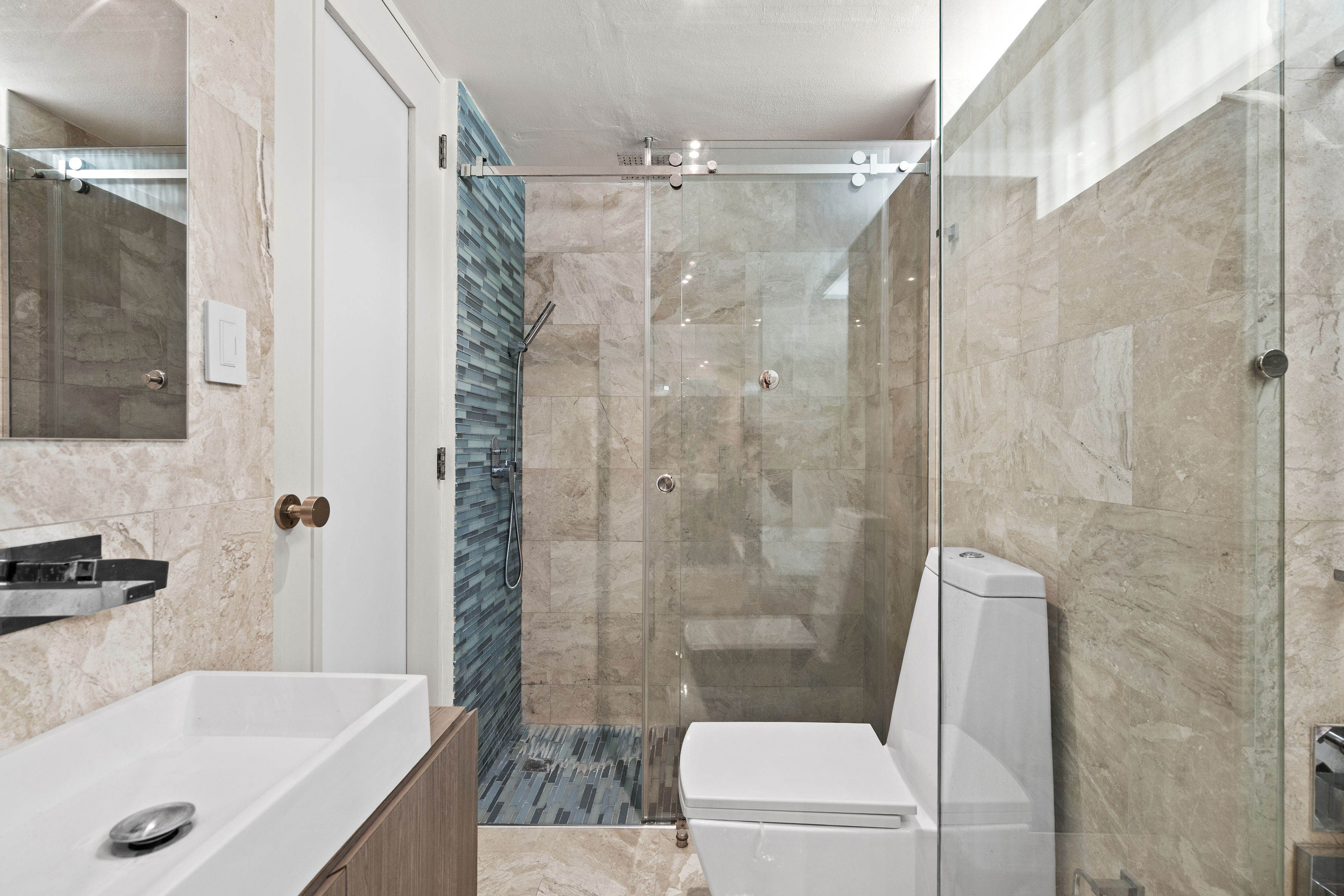 Las Olas Condado renovated bathroom with glass-enclosed walk-in shower