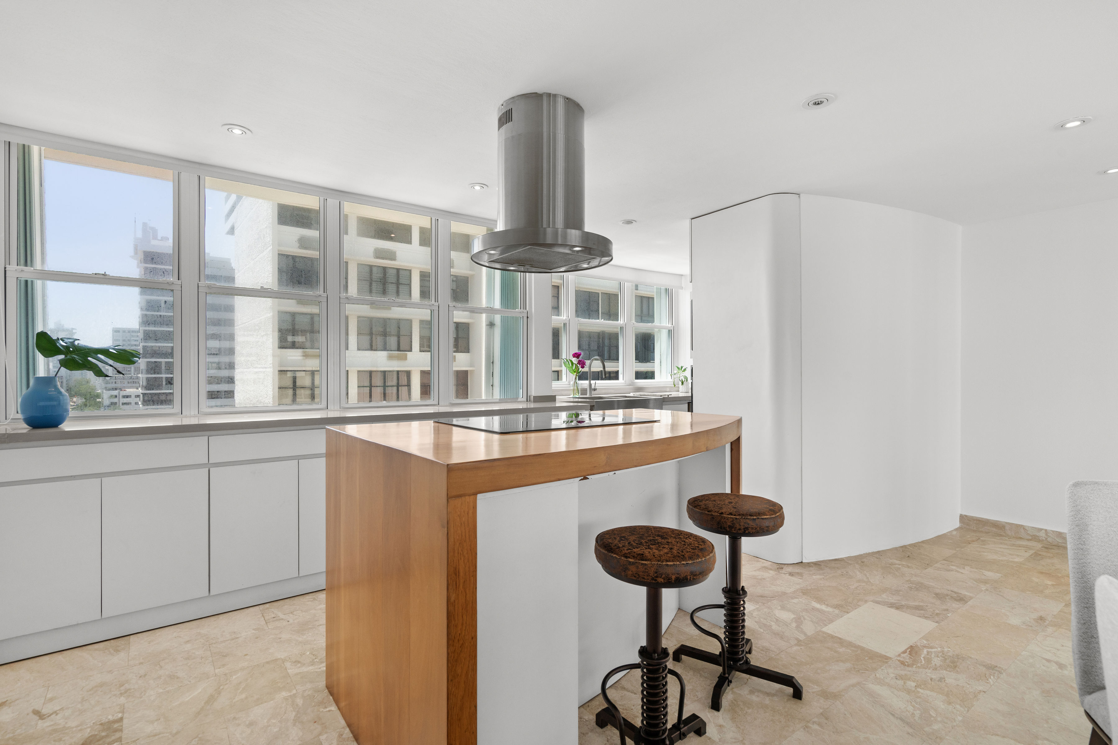 Las Olas Condado modern kitchen with white cabinetry and wood island