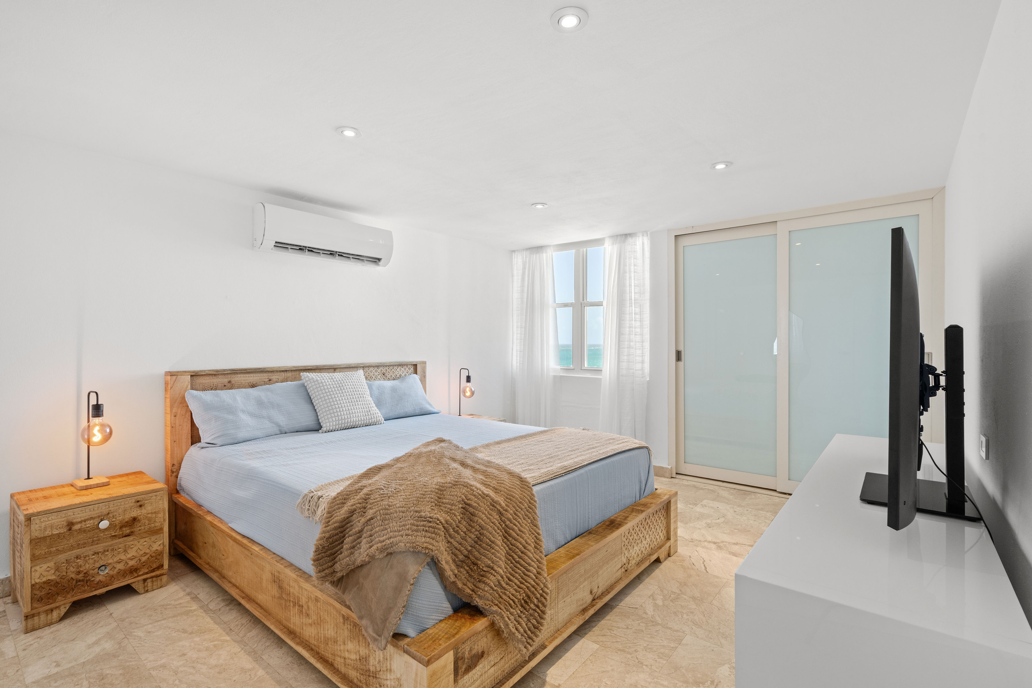 Las Olas Condado primary bedroom with wood furnishings and natural light
