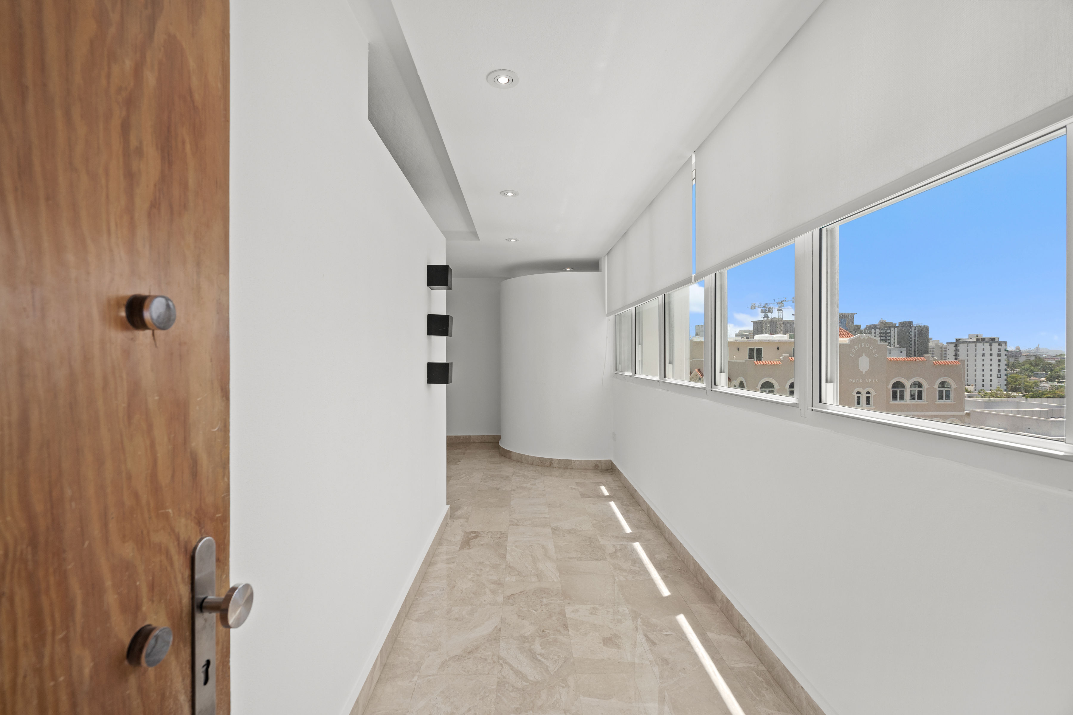 Las Olas Condado entry hallway with floor-to-ceiling windows and city views