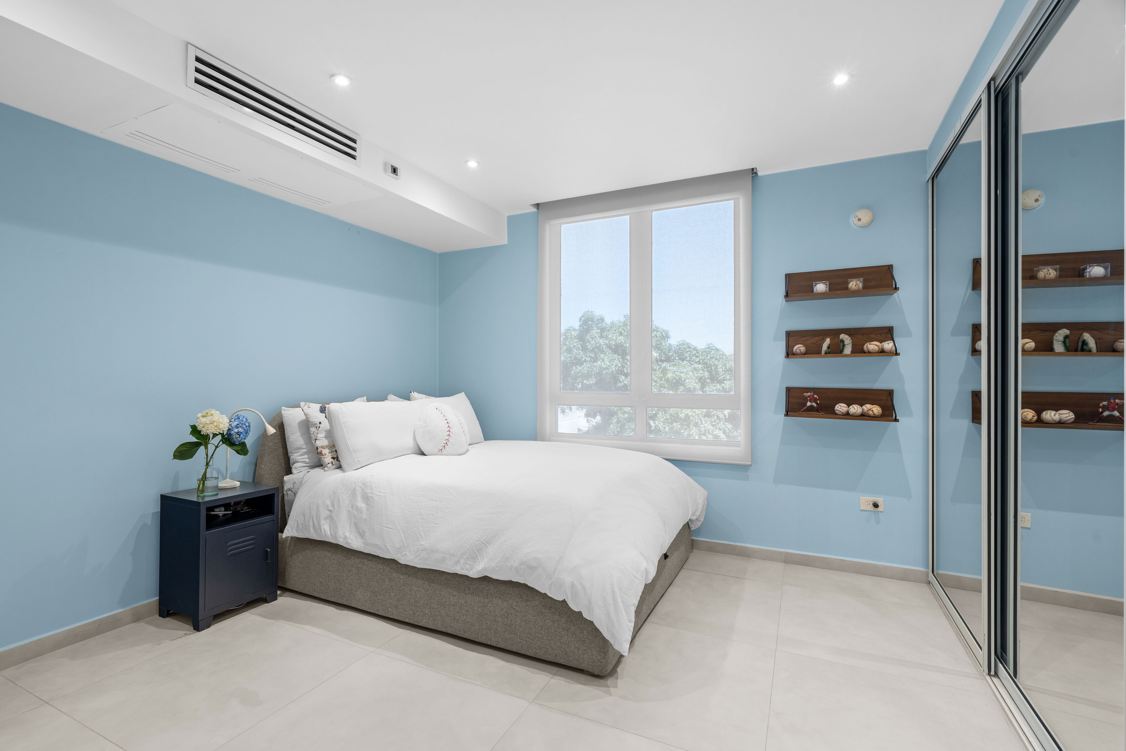 Casa Cervantes 2 | Light-filled secondary bedroom with mirrored closet doors and custom display shelving