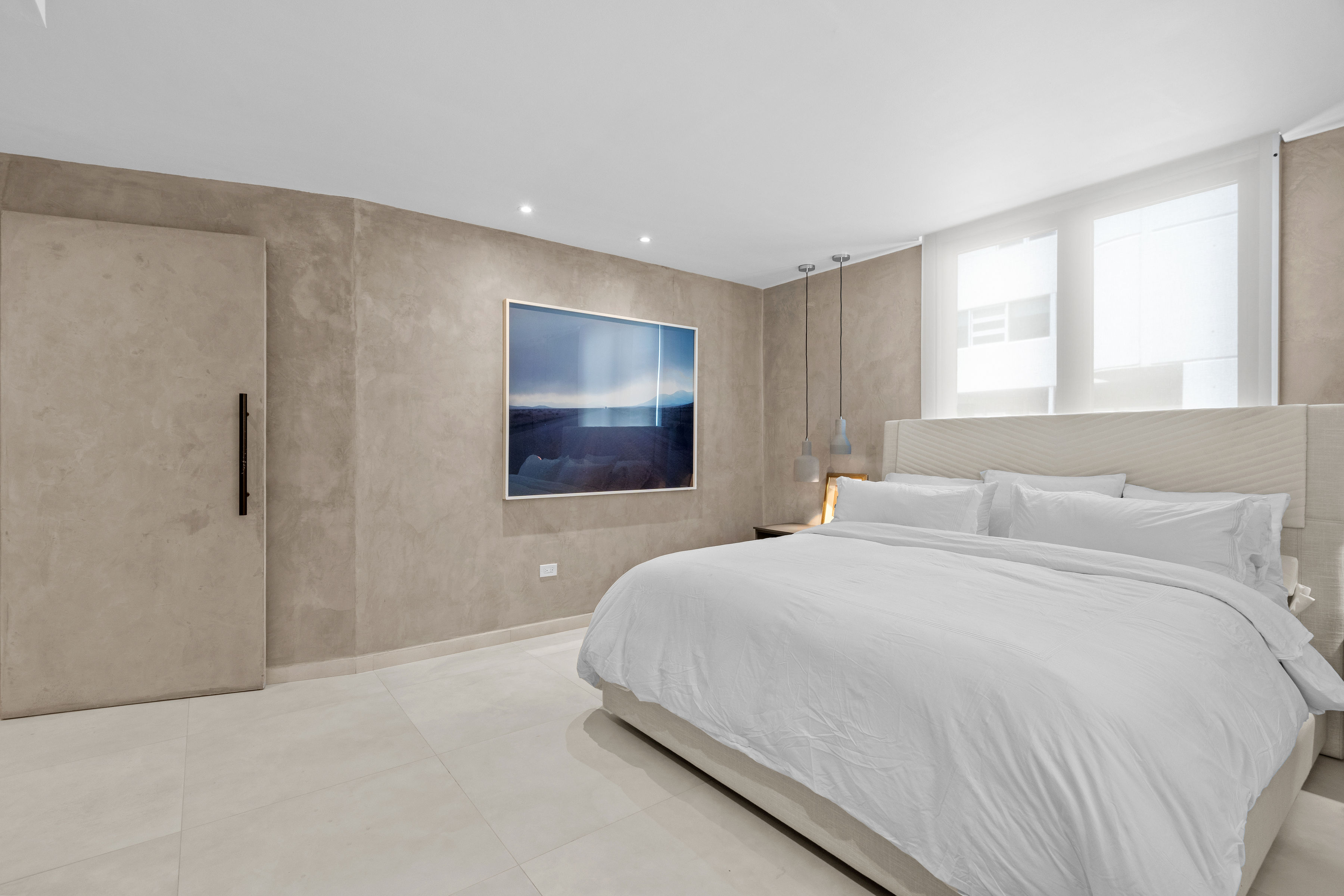 Casa Cervantes 2 | Primary bedroom with textured feature walls, natural light, and minimalist design