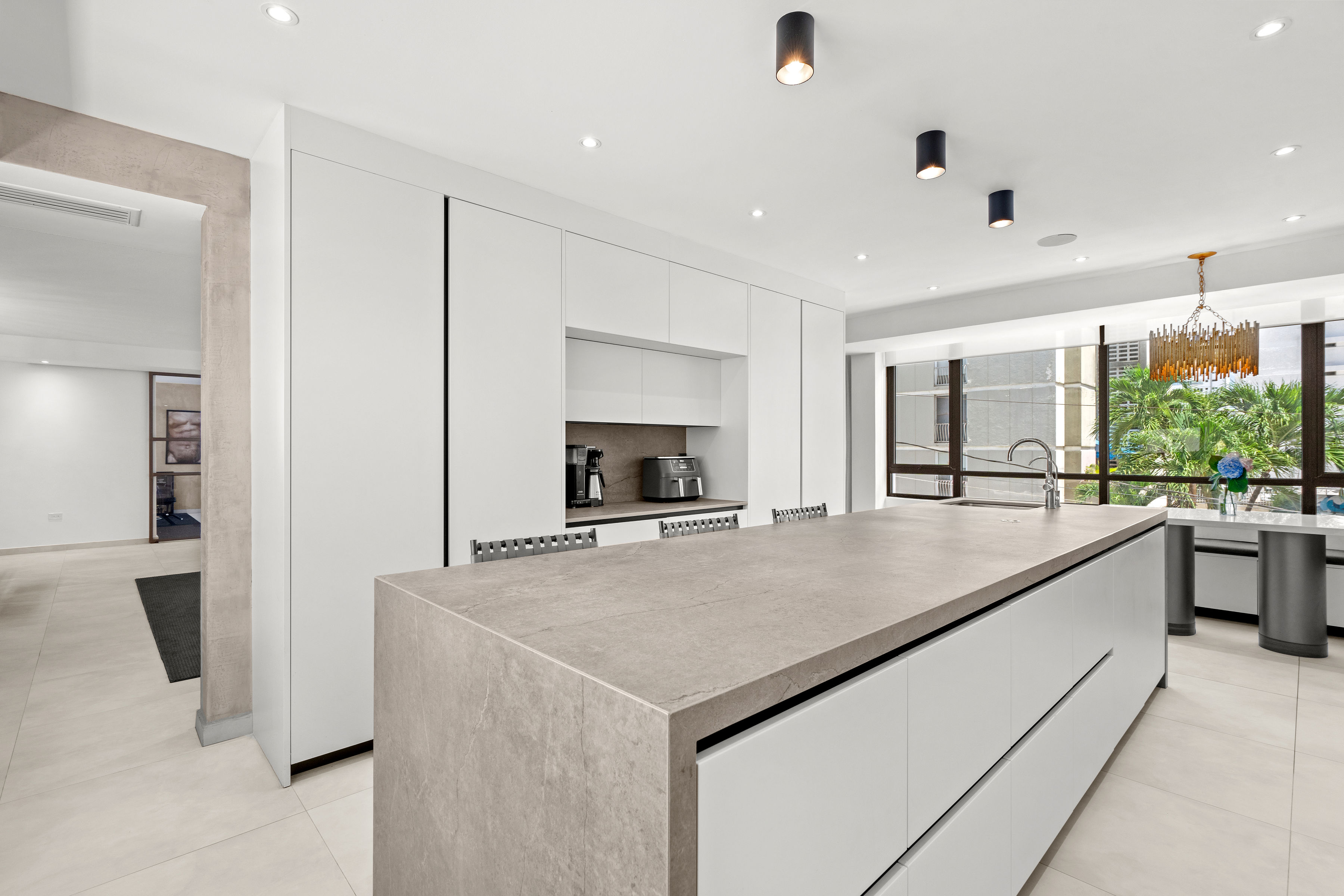 Casa Cervantes 2 | Contemporary kitchen with oversized island, custom cabinetry, and integrated appliances
