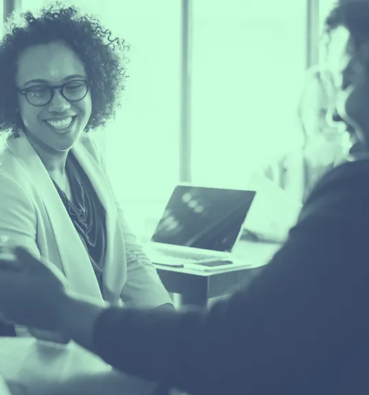 A woman sitting at a table in front of a laptop computer.