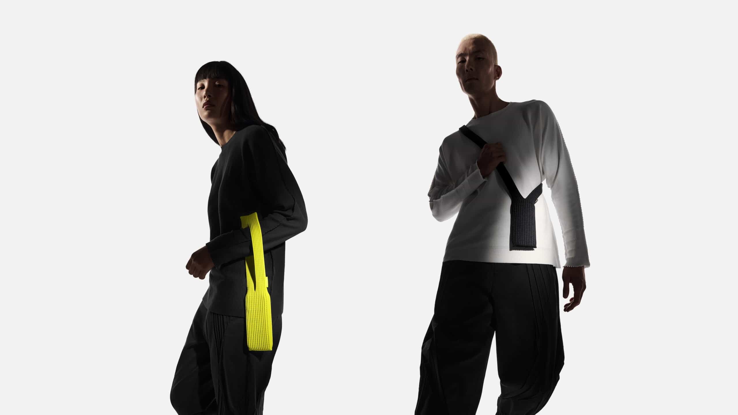 Models wearing Apple iPhone Pocket accessories by ISSEY MIYAKE, shown in lemon yellow and black long-strap designs as wearable tech fashion