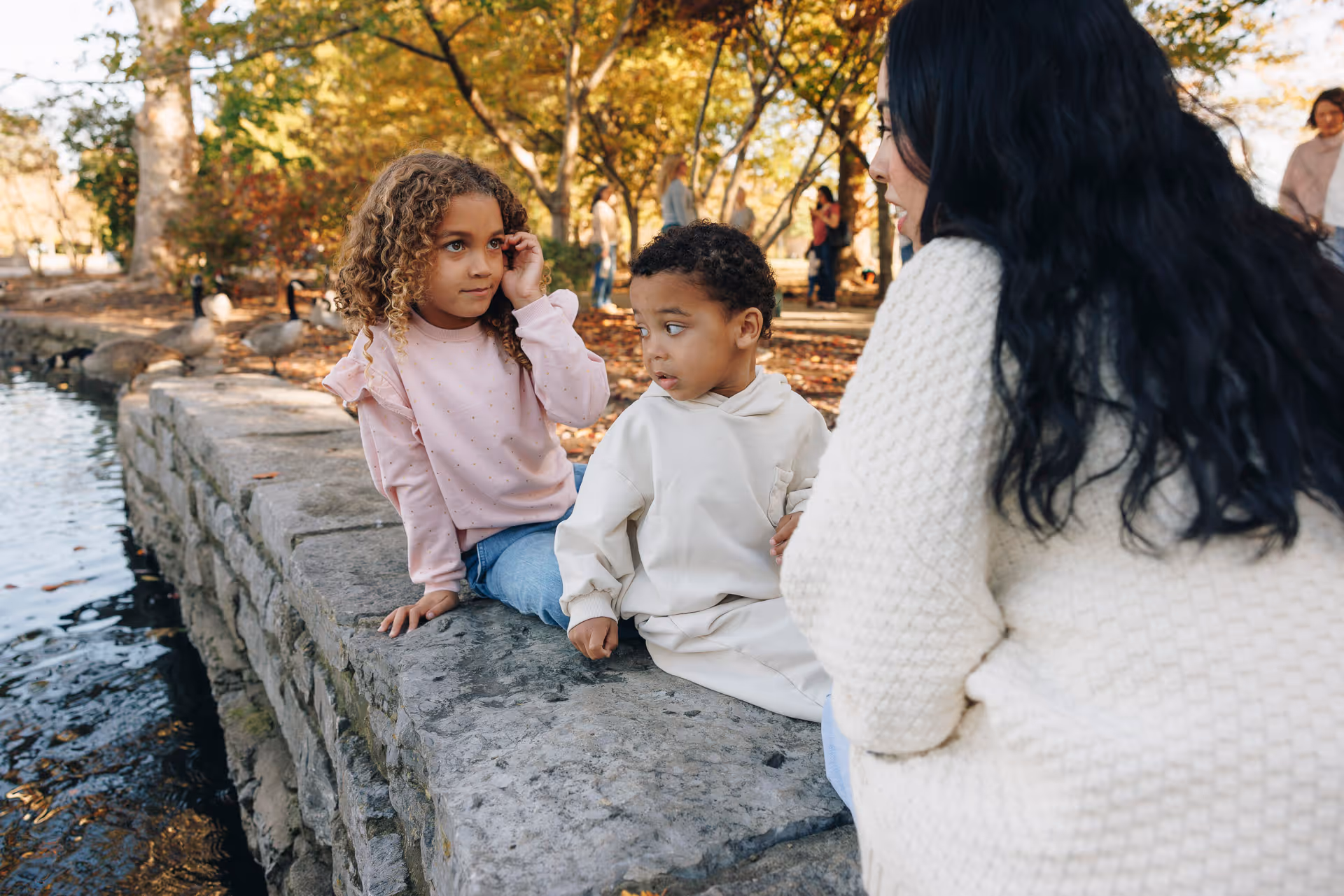 Nanny watching kids at a nearby park by a small river