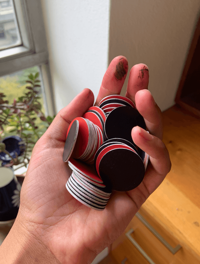 Hand holding recently painted black and white game tokens.