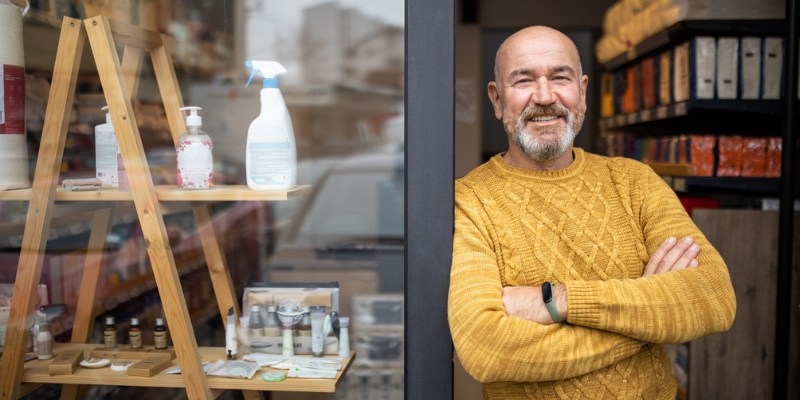 Small business owner leaning on door frame smiling after accessing Bizcap's Line of credit ultra