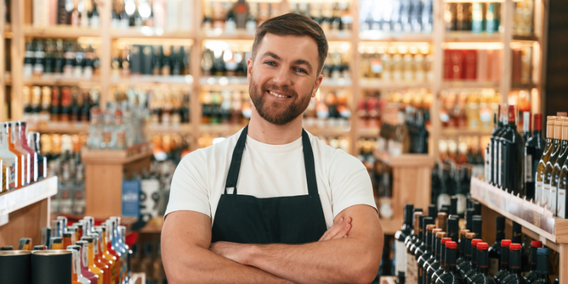 beverage store owner smiling with shelves stocked after a Bizcap Line of Credit