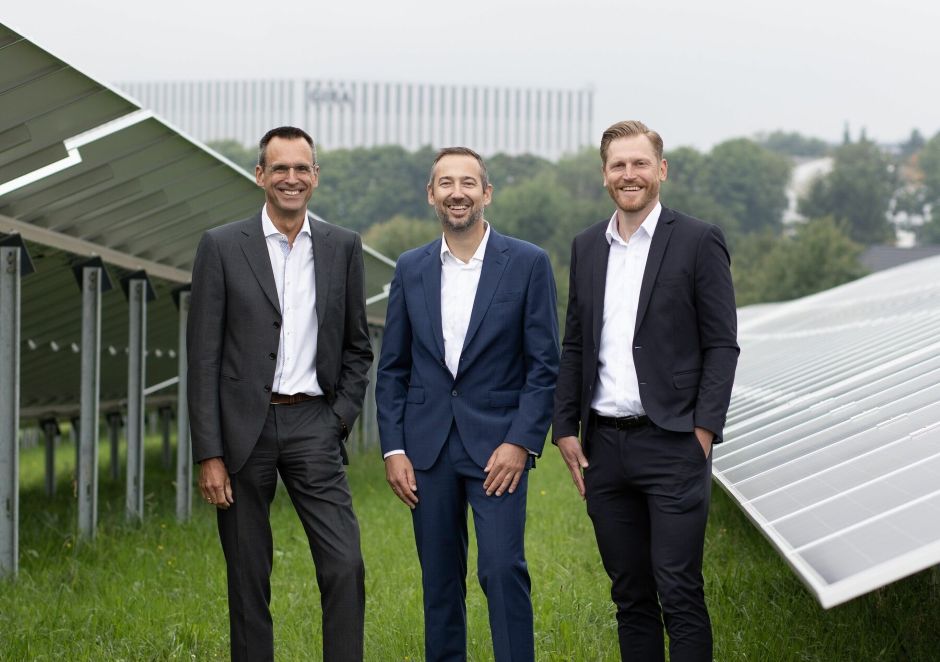 Gira Solarpark: Drei Mitarbeiter, in der Mitte Geschäftsführer Dominik Marte, stehen zwischen den geständerten PV-Modulen der Anlage anlässlich der Einweihung der Anlage im Juli 2025.