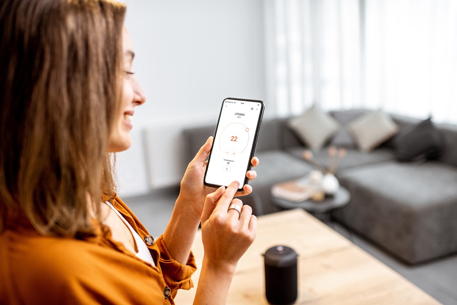 Frau mit Handy bei der Steuerung der Thermostate