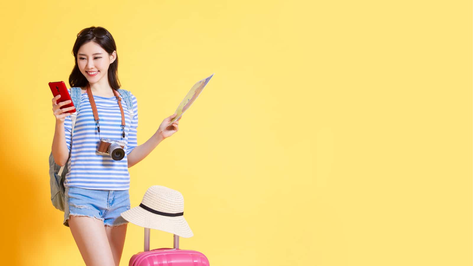 Traveler checking a phone while holding a map and carrying a camera