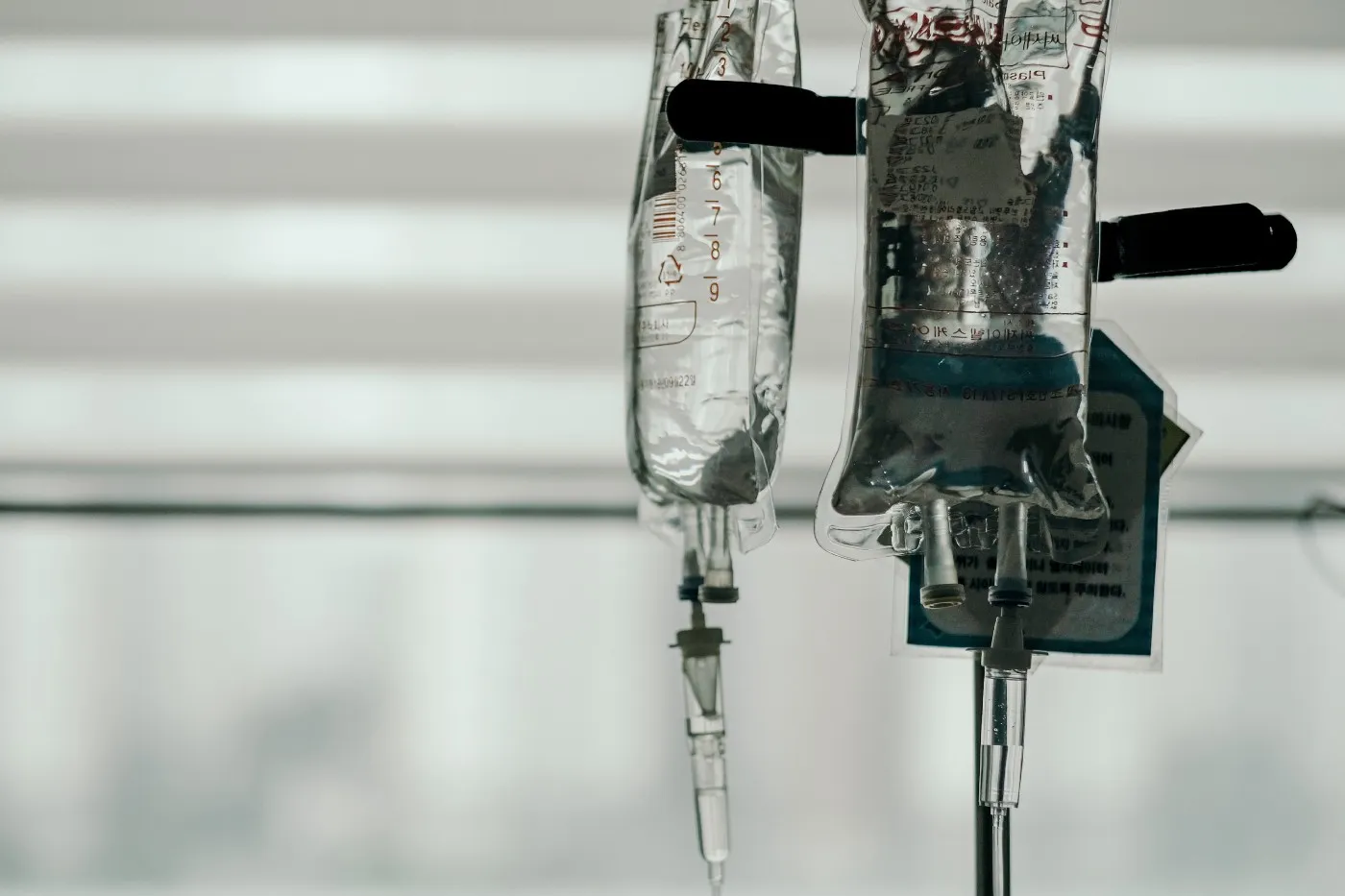 Black and white photo of intravenous fluid bags hanging on rack.