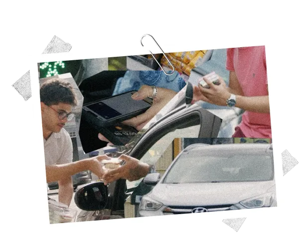 Young man leaning into car window handing cash to driver with a payment terminal nearby at a car service point.