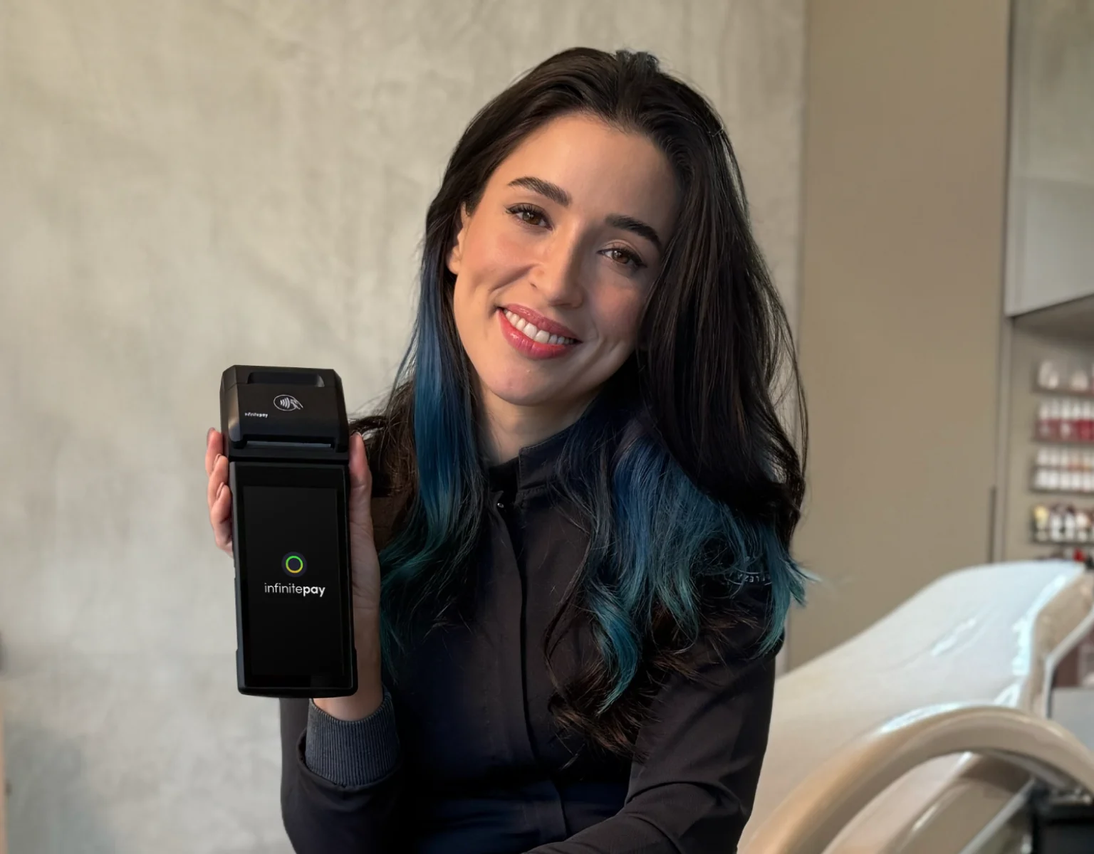 Maquininha de cartão InfinitePay em destaque, iluminada por um feixe de luz, cercada por pedras douradas e escuras em um fundo escuro.