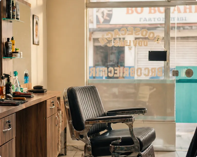 Empty vintage barber chair inside a classic barbershop with wooden cabinets and grooming products.