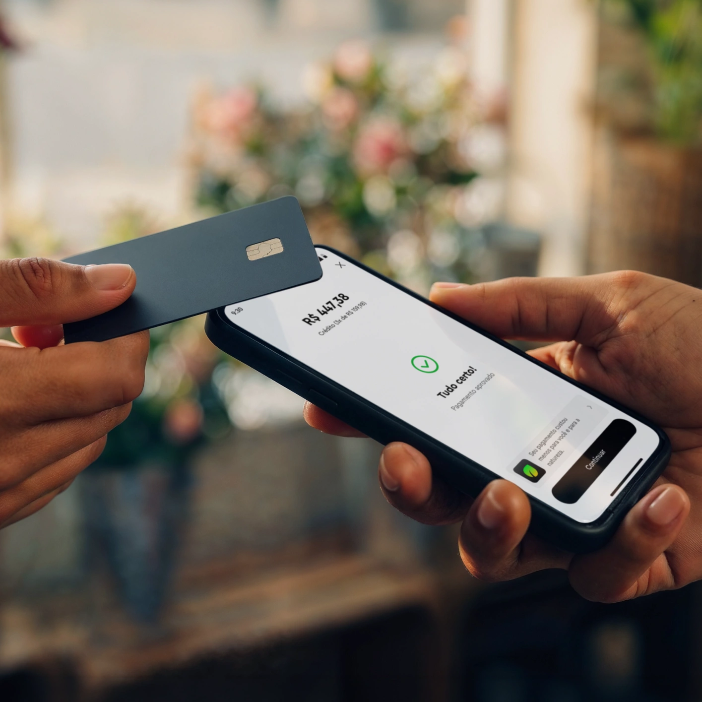 Person holding phone showing payment success screen and another holding contactless payment card.