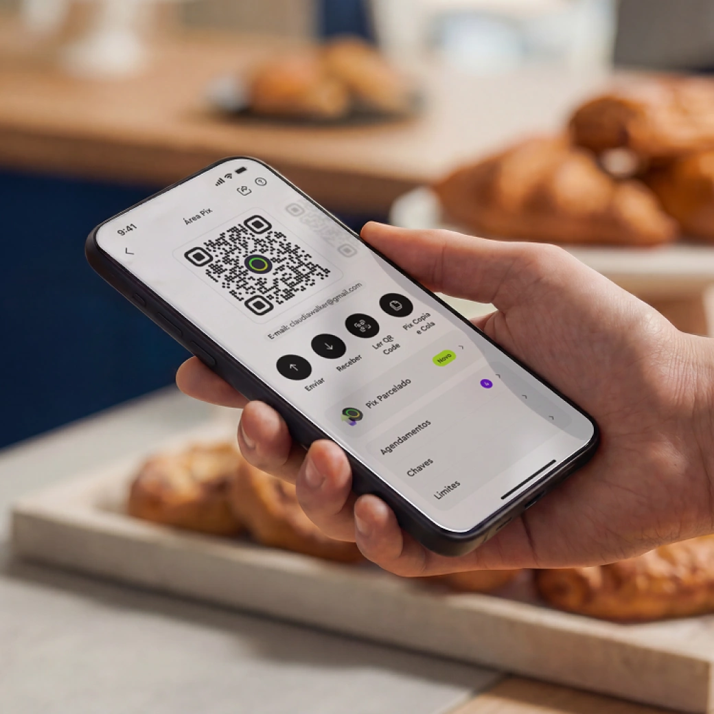Hand holding smartphone displaying a Pix payment QR code on a financial app screen.