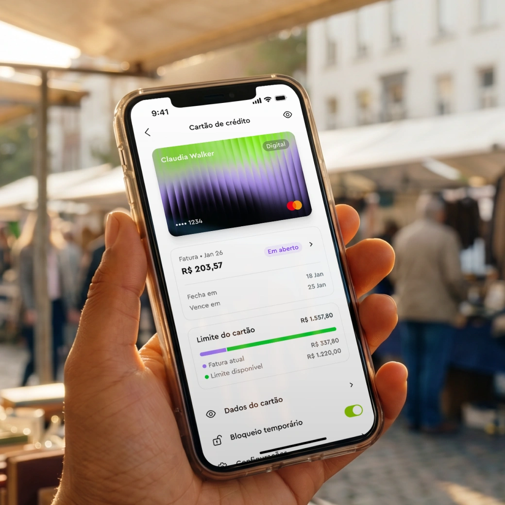 Mobile screen showing a digital credit card and balance details in a finance app, held by a hand outdoors.