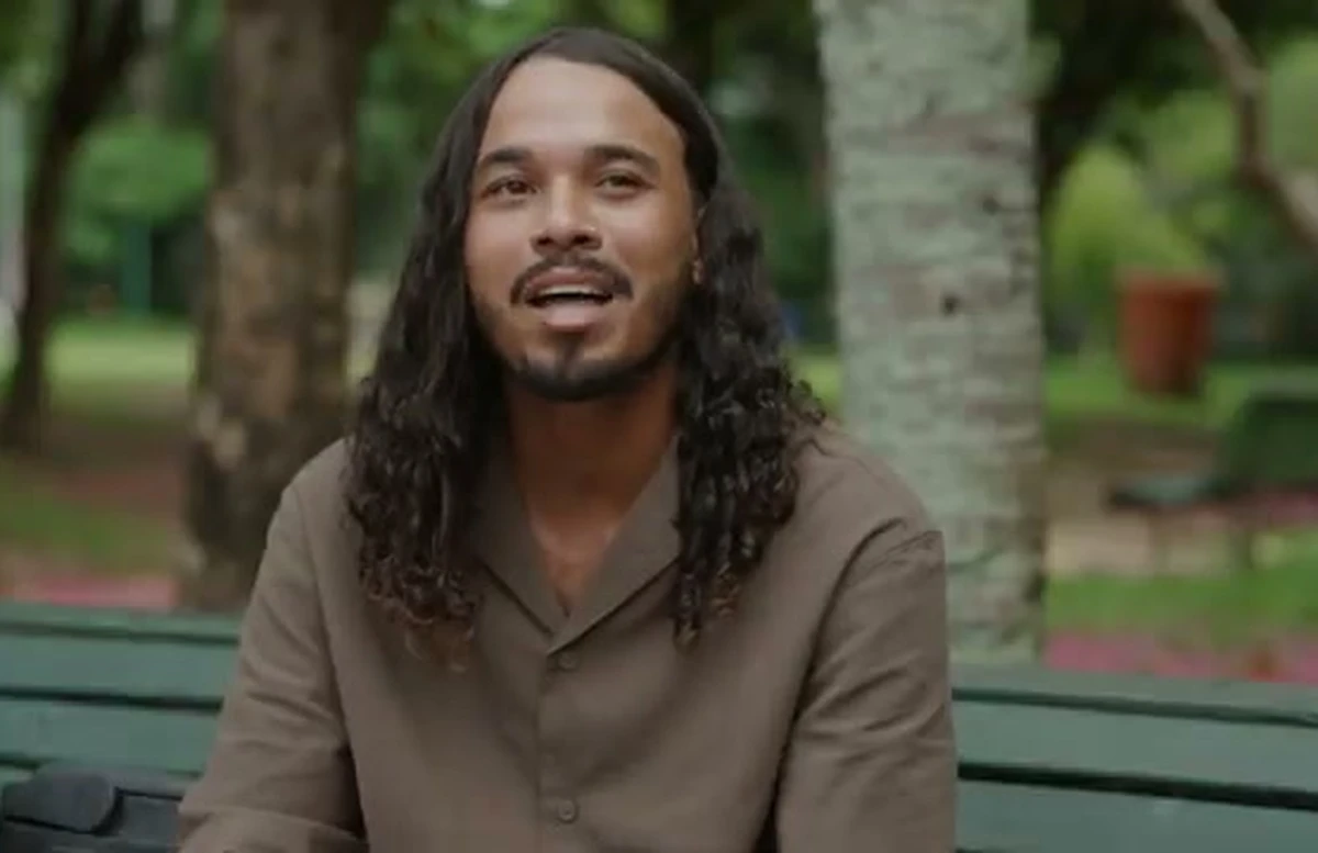 Felipe Marques, vendedor ambulante, sorrindo sentado em um banco de praça arborizada