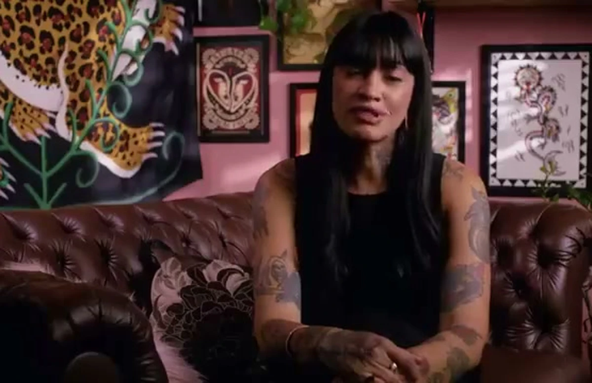 Laila do Amaral, tatuadora, sentada em sofá de couro no seu estúdio de tatuagem