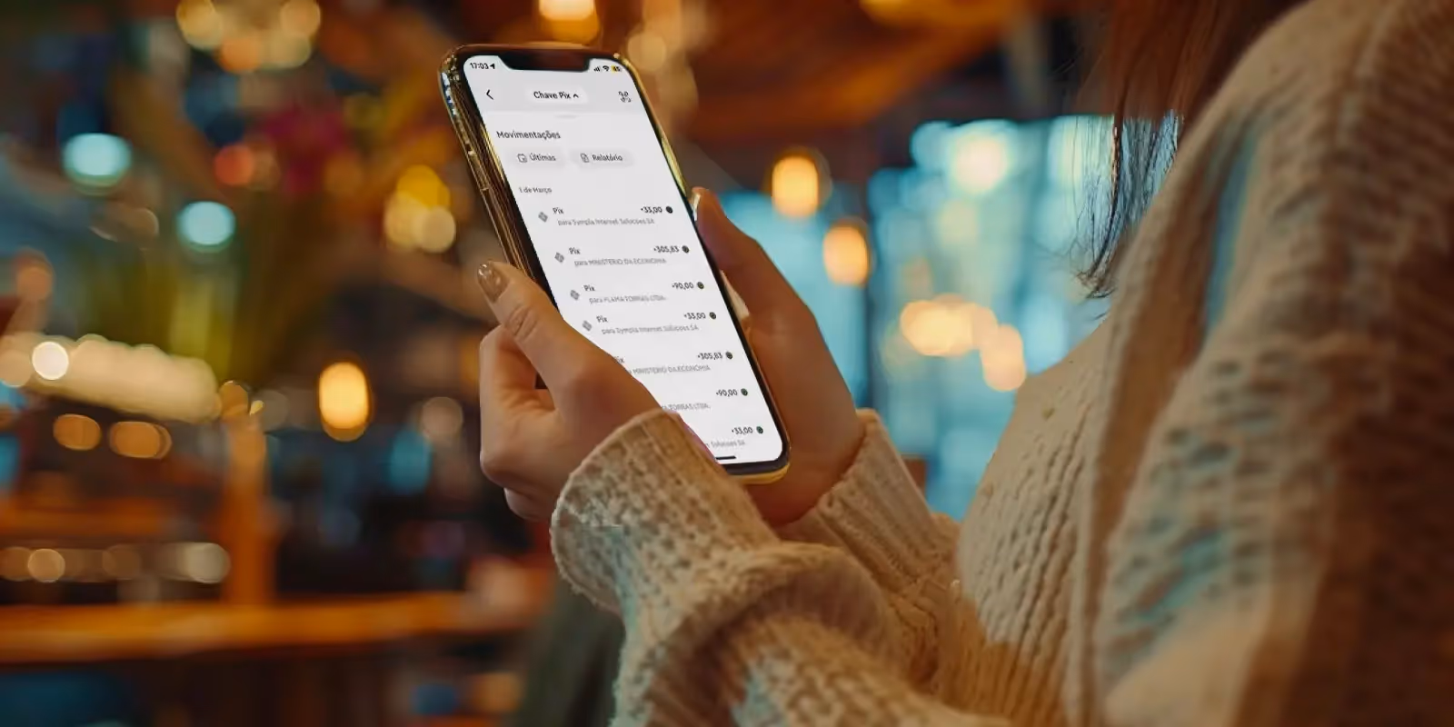 na imagem, em zoom, uma mulher segurando um celular com a tela mostrando como recebe por pix na conta inteligente da InfinitePay