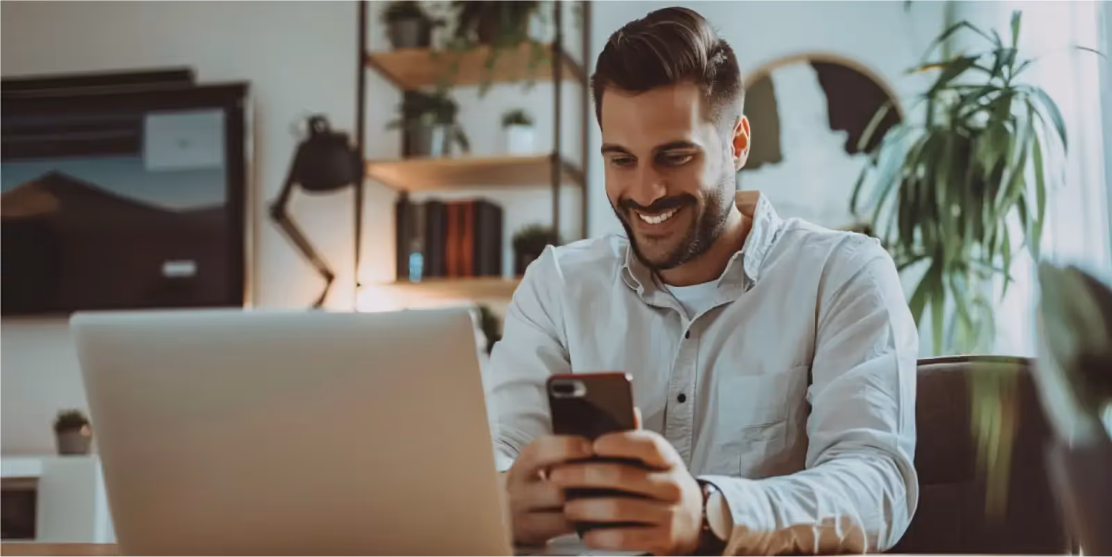 Homem olhando seu smartphone e sorrindo por ter escolhido o melhor banco digital para suas necessidades financeiras.