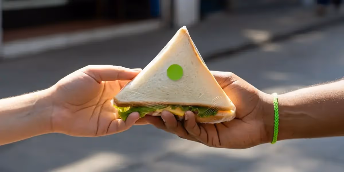 lanches para vender na rua: sanduíche triangular embalado sendo entregue de uma mão para outra.