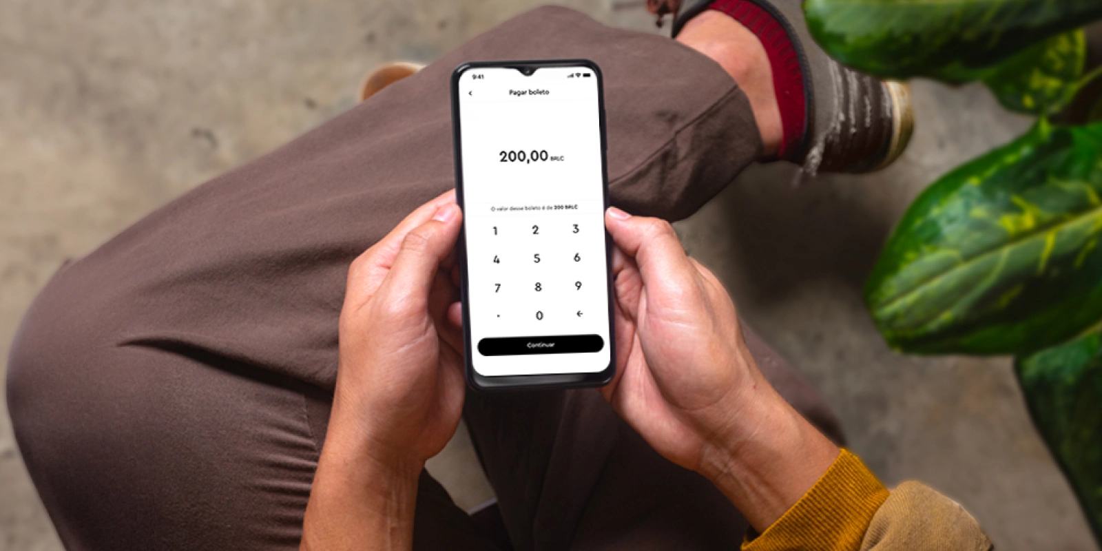 boleto bancário: uma pessoa sentada com o celular na mão mostrando a seção de boletos no app da InfinitePay