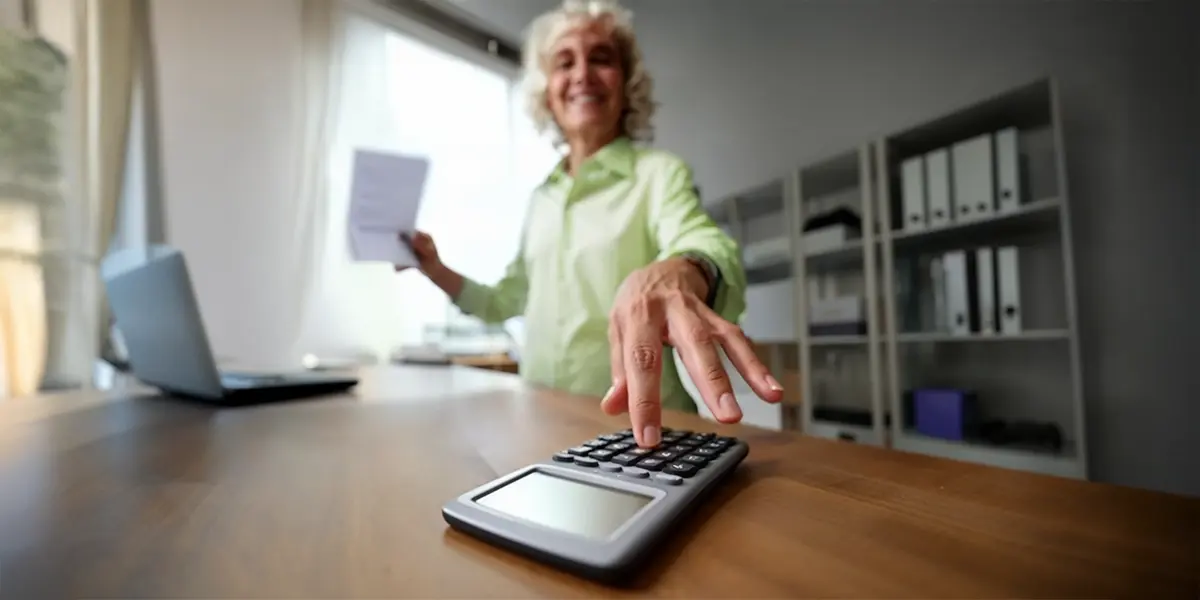 mulher em seu escritório em casa, buscando sua calculadora após ler o artigo "como calcular o ROI".