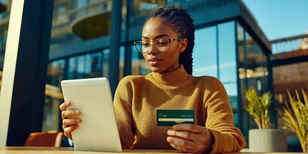 Mulher segurando um tablet com um cartão na mão, simbolizando a pesquisa por "quando o consumidor tem direito à devolução do dinheiro"