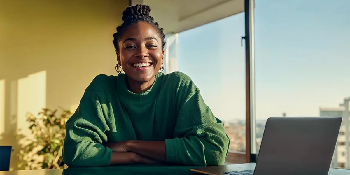 Mulher de camiseta verde, sentada na frente de um computador simbolizando a pesquisa "o que é infoproduto"