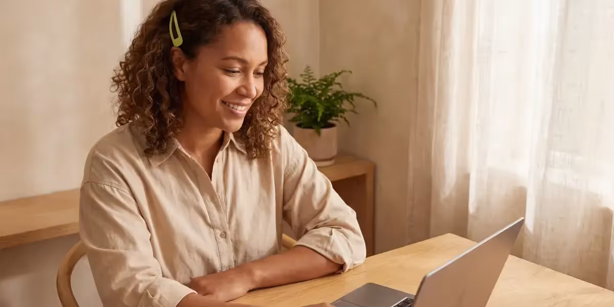 Mulher sorridente analisando investimentos em cdb curto prazo no notebook.