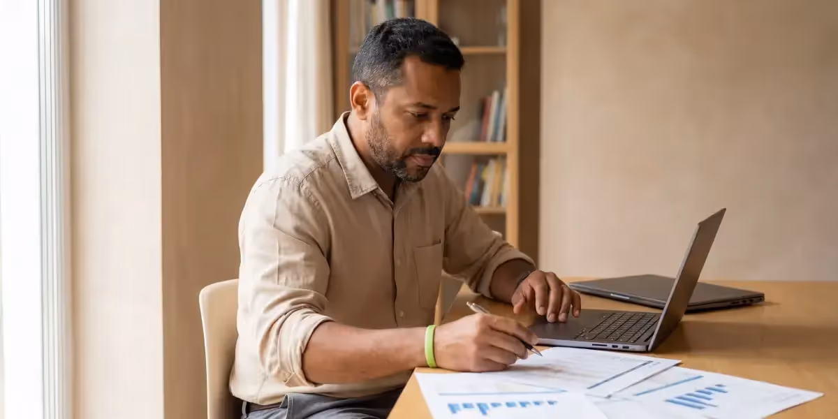 Homem analisando gráficos e planilhas no notebook sobre tabela ir cdb.
