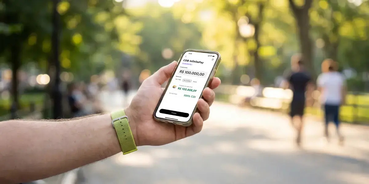 Pessoa segurando celular com app de investimento aberto analisando quanto rende o CDB por mês.