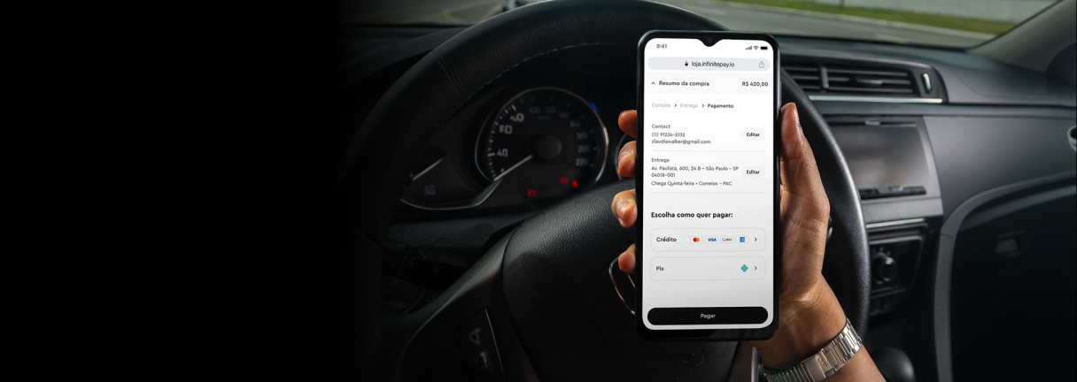 Hand holding smartphone showing payment screen inside a car with dashboard and steering wheel.