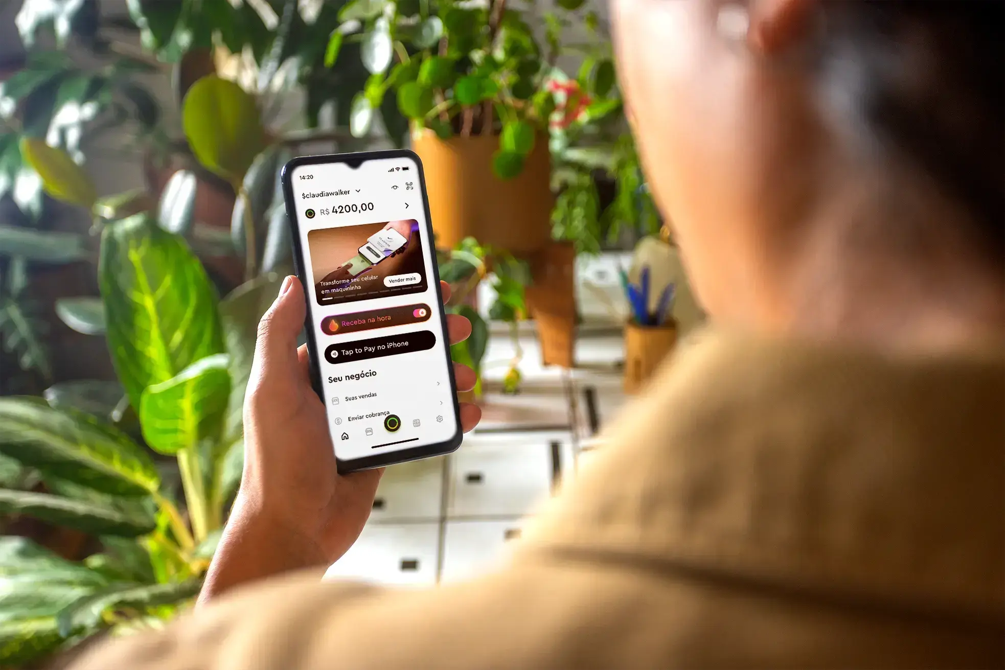 Homem olhando seu celular, que mostra a interface da conta PJ gratuita da InfinitePay.