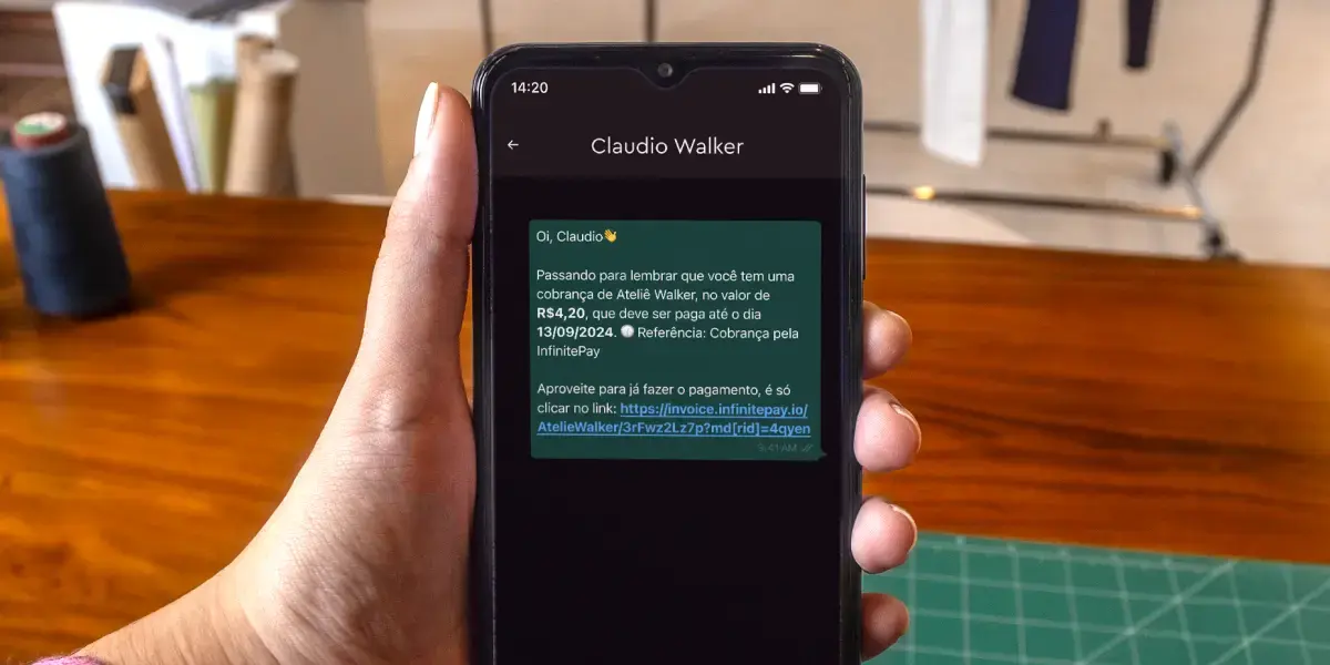 Mão segurando um celular, cuja tela mostra uma mensagem de cobrança, ilustrando uma forma de usar script de cobrança.