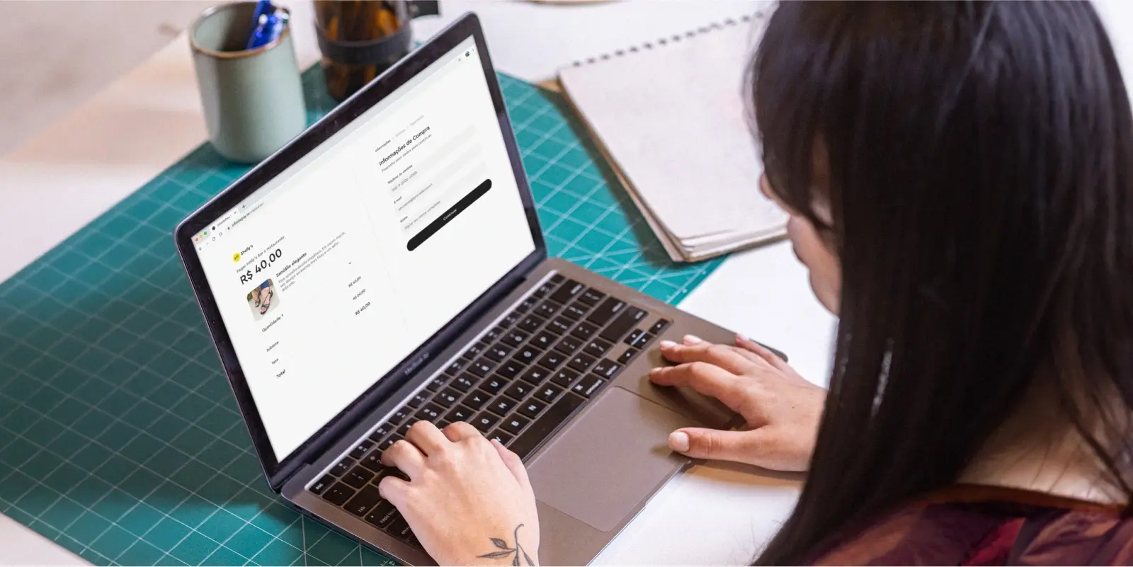 Pessoa usando um laptop para completar uma compra online, com a tela mostrando a página de checkout e o valor de R$ 40,00.