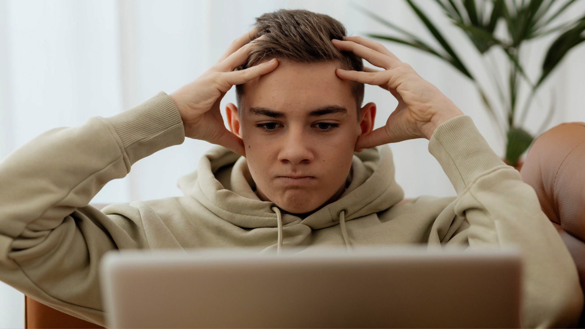 An image of a visibly frustrated student staring at a laptop screen.