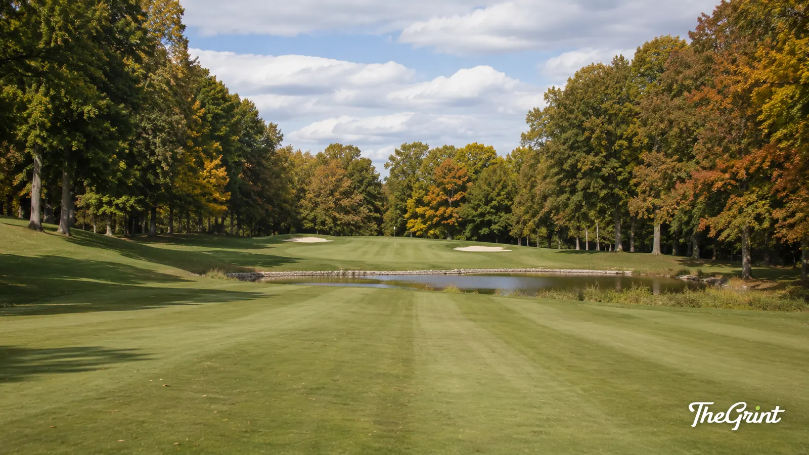 Parkland golf hole with a pond and autumn foliage