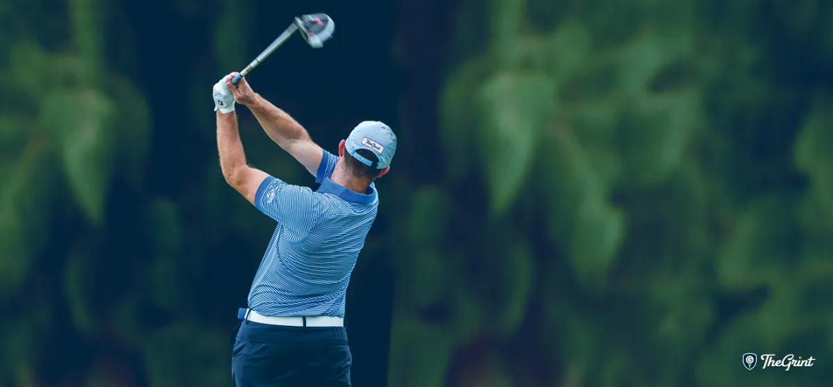Golfer finishing a driver swing in front of a blurred green background, TheGrint logo in the corner