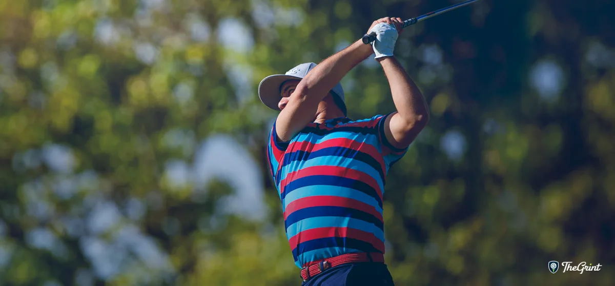 Golfer in a striped polo following through on a swing, TheGrint logo in the corner