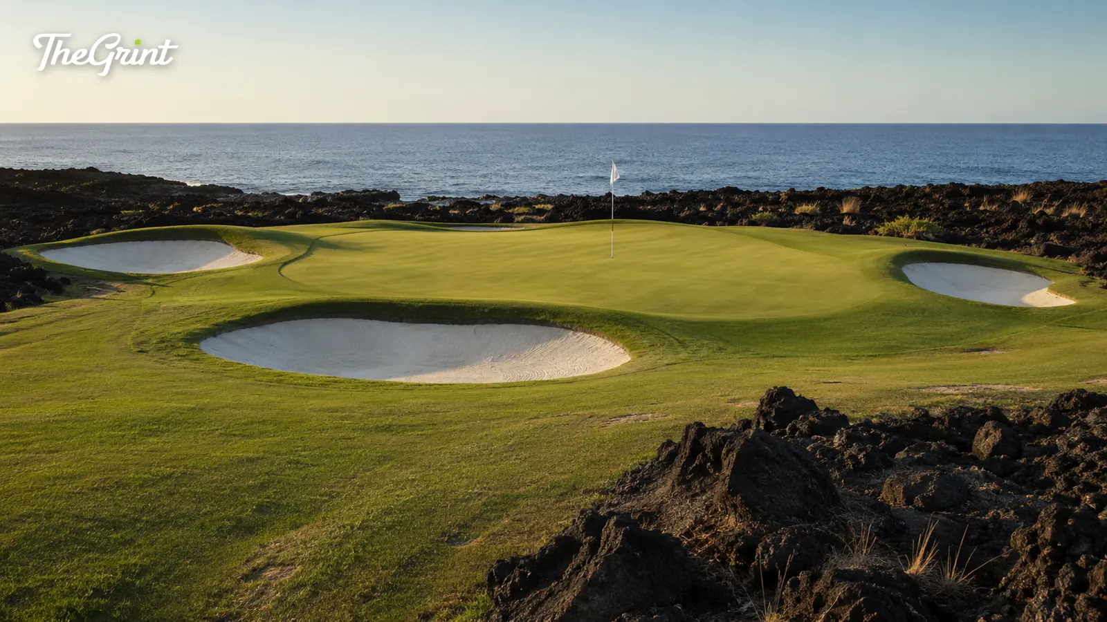 Oceanside golf green with white bunkers on dark volcanic rock