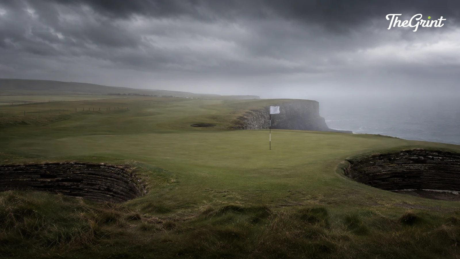 Links golf green with deep pot bunkers on a cliff edge under storm clouds