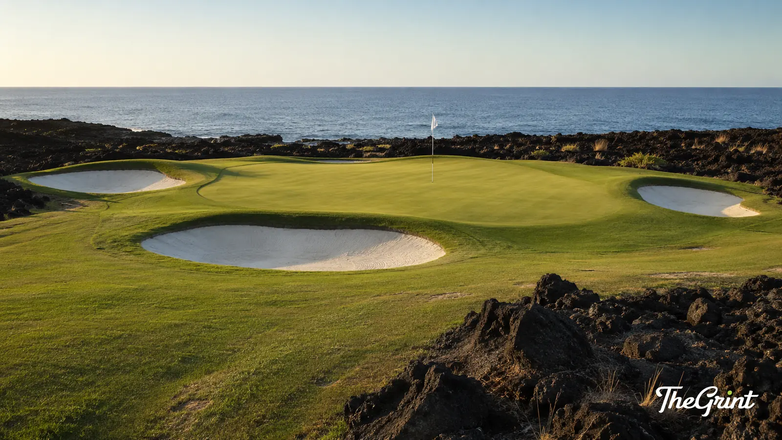Oceanside golf green with white bunkers on dark volcanic rock
