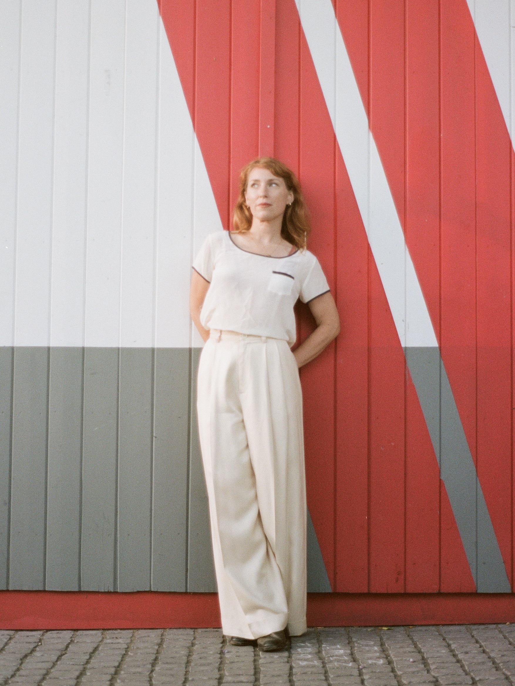 image of a red haired woman in a white top against a red grey and white patternedbackground